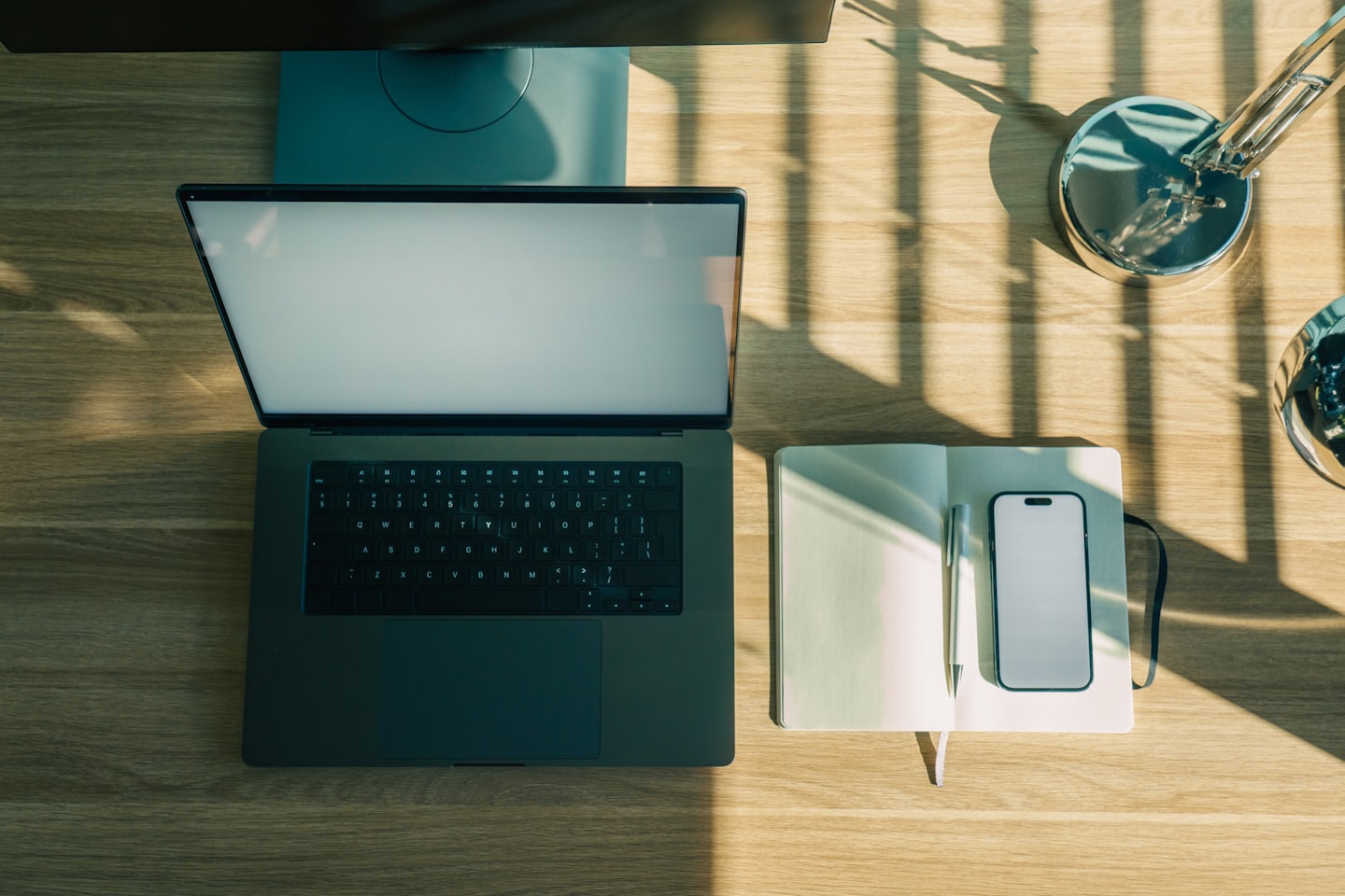 Laptop, notebook e smartphone disposti su una scrivania di legno.