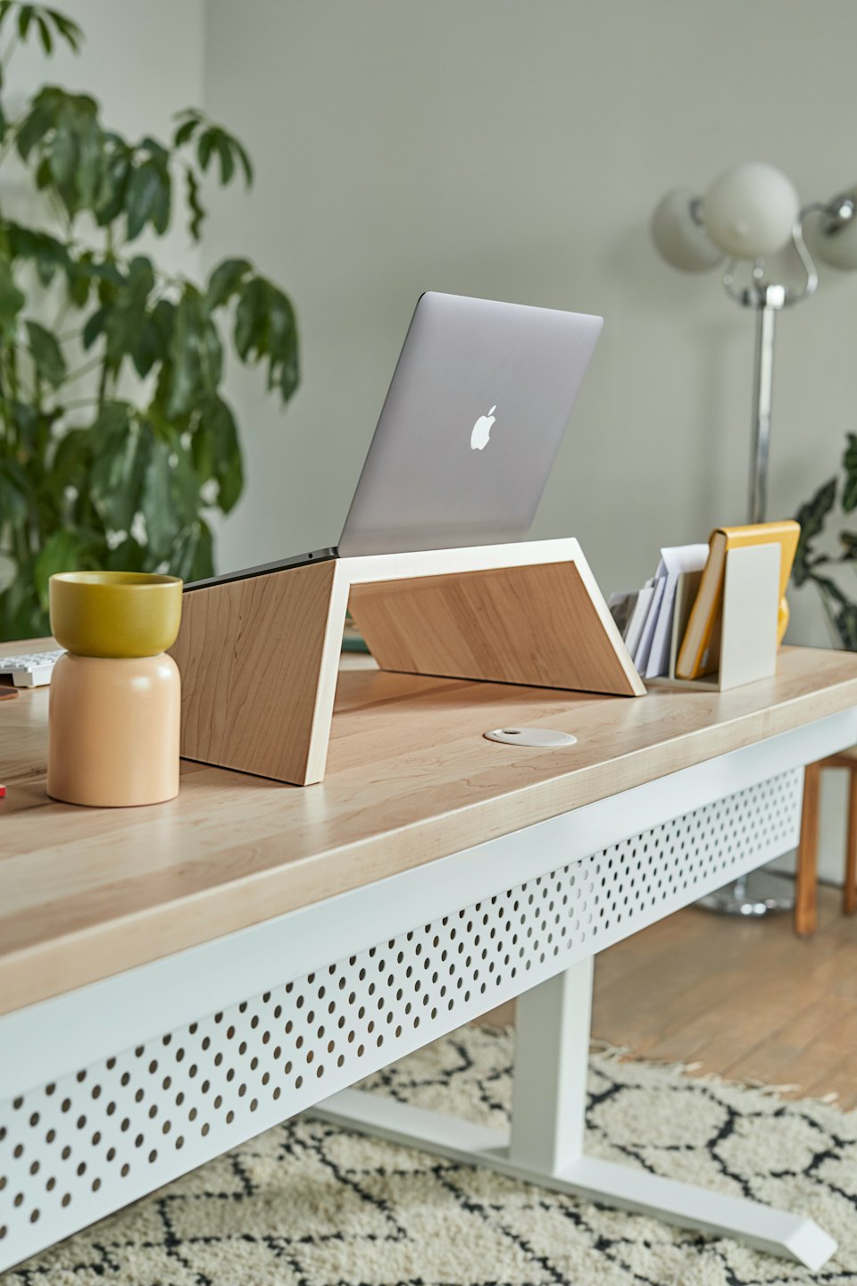 Computer portatile su un supporto in legno chiaro su una scrivania moderna.